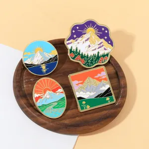 Détail de quatre pins en émail avec paysages naturels sur un plateau en bois