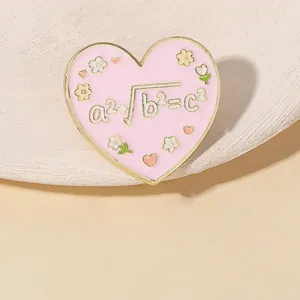 Macro shot of heart-shaped pink enamel pin featuring math formulas and floral accents