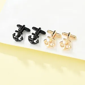 Detail view of anchor cufflinks in black and gold finishes on a white tiered stand
