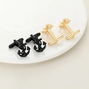 Detail of anchor cufflinks in gold and black with rope texture on a white tray