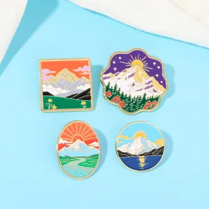 Détail de quatre épingles en émail avec paysages de montagnes et vagues sur fond bleu clair