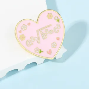 Detail of pink heart-shaped enamel brooch with golden math formula design and small flowers