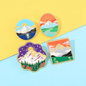 Vue détaillée de quatre pins en émail illustrant des montagnes enneigées et un coucher de soleil