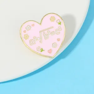 Macro shot of pink heart enamel brooch with mathematical formula a²+b²=c² and gold trim