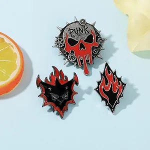 Détail de trois broches en émail de style punk avec crâne et flammes sur fond bleu clair