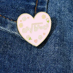 Detailed view of pink heart enamel pin with math formula on denim fabric jacket