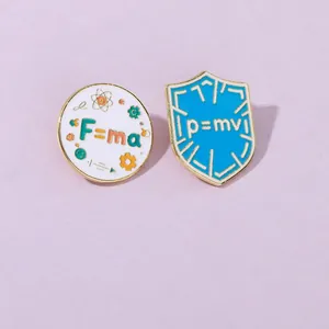 Close-up of physical formula enamel pins featuring Newton's second law and momentum equations