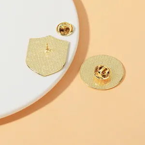 Back view of gold shield and round pins showing textured metal surface and butterfly clasps