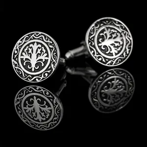 Macro detail of round silver tree cufflinks with black background on mirror surface