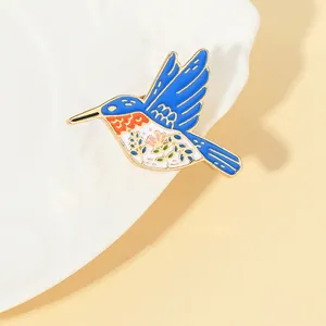 Macro detail of a colorful enamel hummingbird brooch on a white decorative ceramic plate