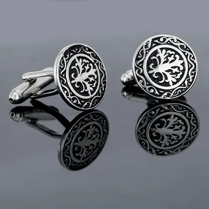 Detailed macro view of silver cufflinks with embossed Tree of Life pattern and vine border