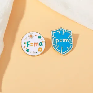 Detail of enamel pins featuring physics formulas F=ma and p=mv with golden edges