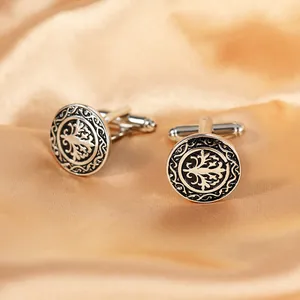 Detailed close-up of vintage silver cufflinks with tree crest on luxury champagne silk
