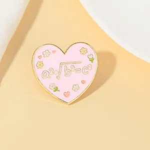 Close-up of pink heart enamel brooch featuring a mathematical formula and tiny floral details