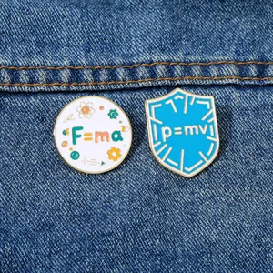 Detail of science enamel pins with physics formulas F=ma and p=mv on denim fabric