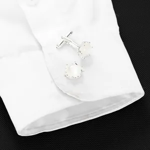 Dettaglio di gemelli a corona in argento con pietra perlata bianca sul polsino della camicia