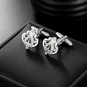 Macro view of silver crown cufflinks with intricate filigree and crystal inlay detail