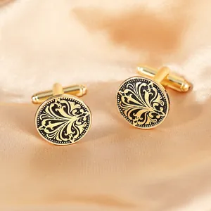 Details runder goldener Manschettenknöpfe mit schwarzem Blumenmuster auf Seide