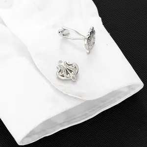 Close-up of silver crown cufflinks with crystals on a white shirt cuff in formal style