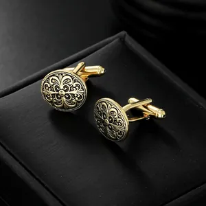 Detailansicht goldener Manschettenknopf mit Fleur-de-Lis Muster auf schwarzer Box