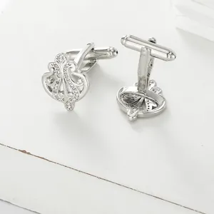 Detailed view of silver crown-shaped cufflinks with white cubic zirconia and T-bar closure
