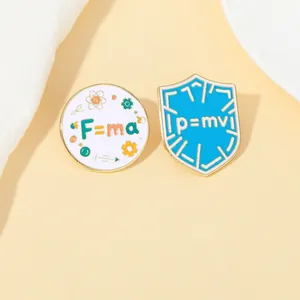 Detail of physics enamel pins featuring F=ma and p=mv formulas with gold metal edges