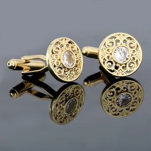 Detail of luxury gold cufflinks with hollow filigree patterns and center crystal stone