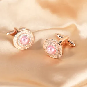 Dettaglio dei gemelli in oro rosa con perla rosa e cristallo su sfondo in raso