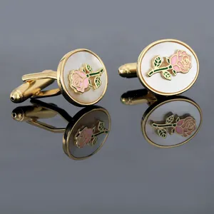 Detail view of gold cufflinks featuring pink enamel rose and pearl-like inlay texture