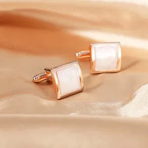 Detail view of square rose gold cufflinks with iridescent white mother of pearl inlay