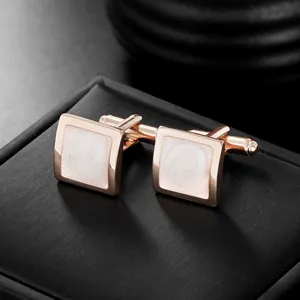 Détail macro de boutons de manchette carrés en or rose avec émail blanc marbré