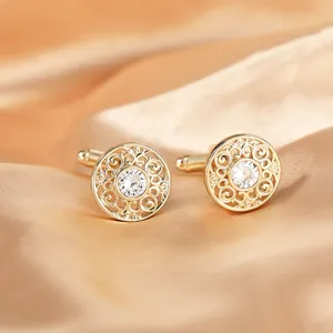 Close-up of luxury gold-plated copper cufflinks with hollow pattern and central crystal