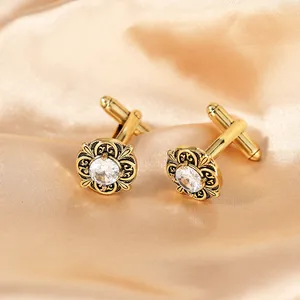 Detailed close-up of gold-plated cufflinks with vintage floral relief and zircon on satin