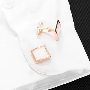 Détail de boutons de manchette carrés or rose avec nacre blanche sur poignet de chemise