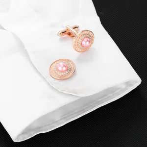 Dettaglio di gemelli in oro rosa con perla rosa e zirconi sul polsino di una camicia