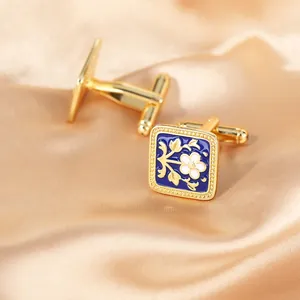 Detail of square gold cufflinks with blue enamel and white floral pattern on silk