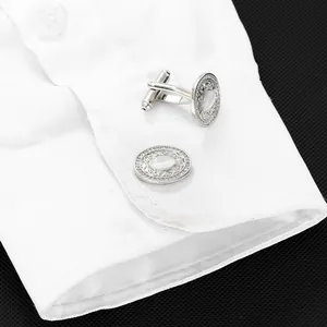 Gros plan de boutons de manchette argentés avec opale et diamants sur chemise blanche