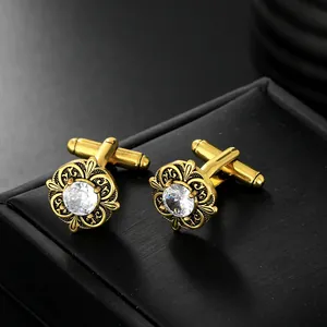 Macro shot of gold cufflinks with floral hollow carving and clear zircon center inlay