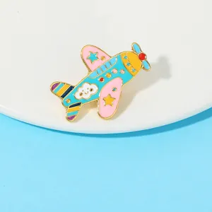 Dettaglio di una spilla in smalto a forma di aereo cartone animato con stelle e nuvole