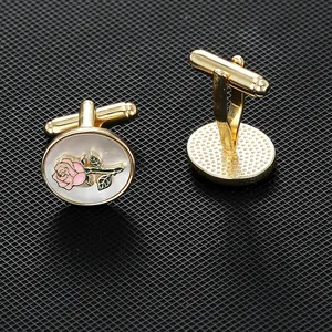 Gold oval cufflinks with white pearl base and pink rose enamel pattern on black mesh background