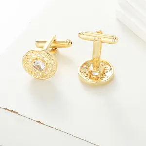 Macro shot of gold-plated copper cufflinks with hollow pattern and crystal stone