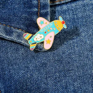 Dettaglio di una spilla in smalto a forma di aereo cartoon su tessuto denim con oro