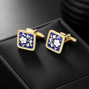 Detail of square gold cufflinks with blue enamel floral pattern on black leather box