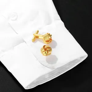 Boutons de manchette nœud tressé doré élégants sur une manchette de chemise blanche