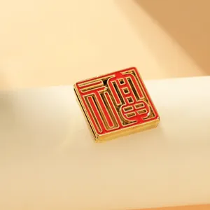 Macro view of a square gold-plated enamel fridge magnet with a cutout Fu character