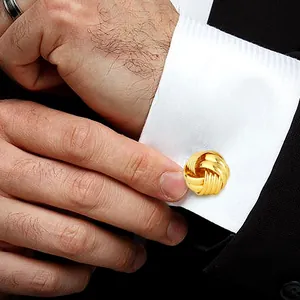 Gros plan de boutons de manchette dorés sur chemise blanche sous une veste foncée