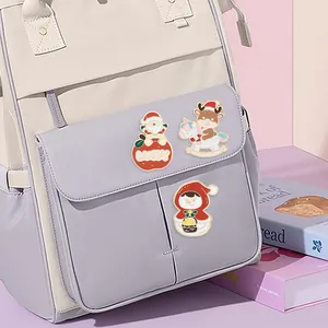 Three Christmas enamel pins set with Santa and reindeer on a beige backpack surface