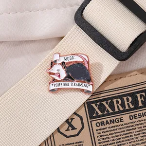 Détail du pin's émaillé opossum sur sangle en toile avec le texte Mood: Perpetual Screaming