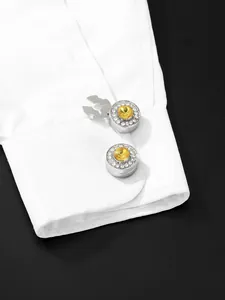 Detail van zilveren knoophoezen met gele steen en pavé-edelstenen op een overhemdmanchet