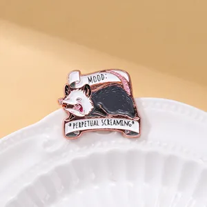 Détail du pin's en émail opossum avec texte Perpetual Screaming sur une assiette en céramique